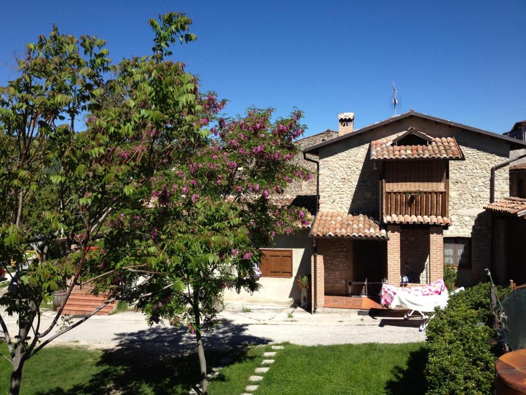 a large stone house with a tree in the yard at Il Fienile in Barete