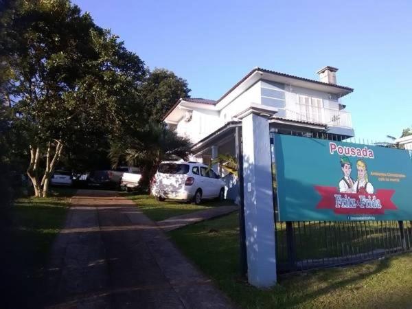 a sign in front of a house with a white car at Pousada Fritz & Frida in Santa Cruz do Sul