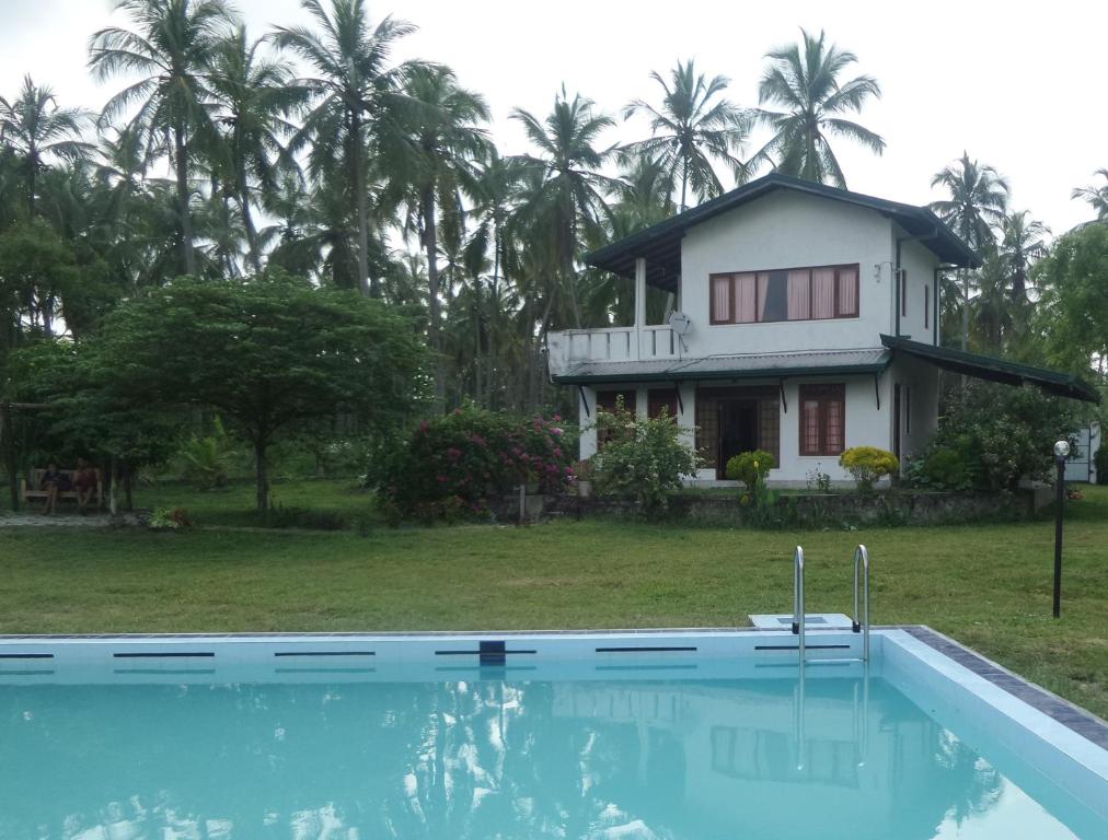 uma casa e uma piscina em frente a uma casa em cocoworld bungalow em Bandara Koswatta