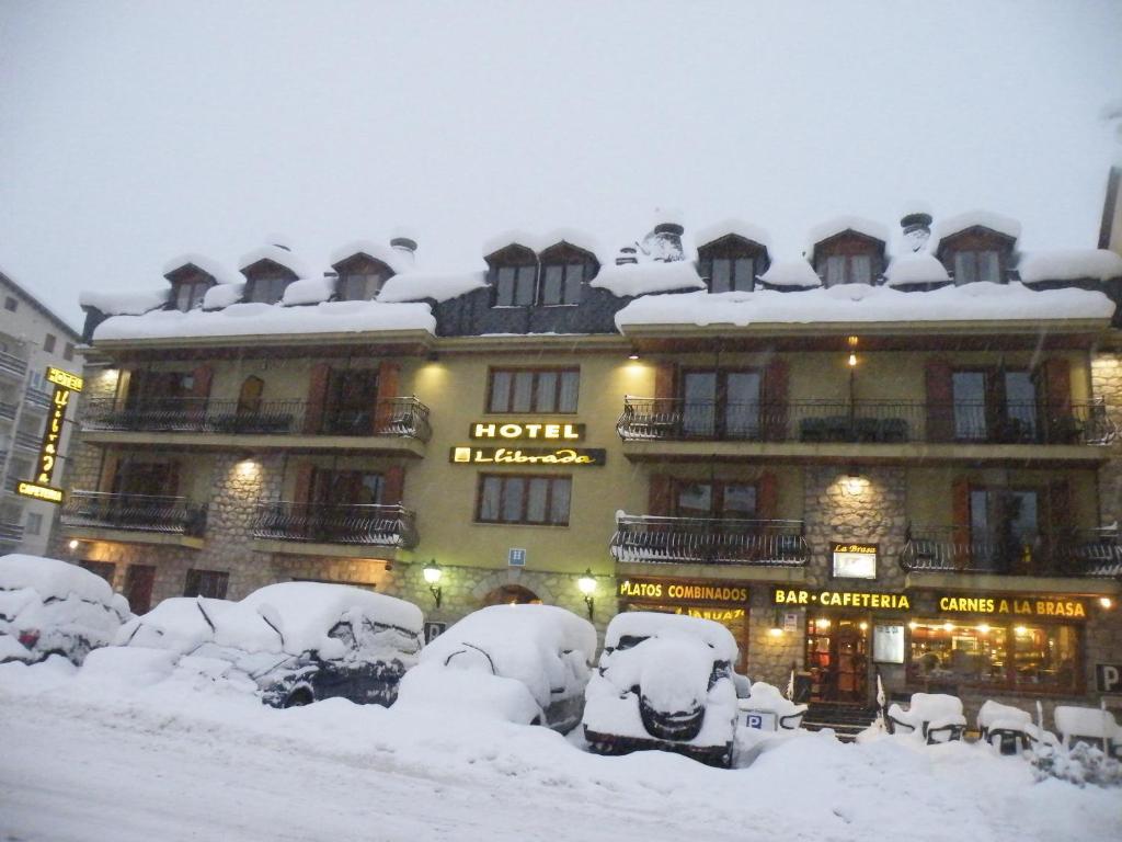 uma neve coberta edifício com carros cobertos de neve em frente em Hotel Llibrada em Benasque