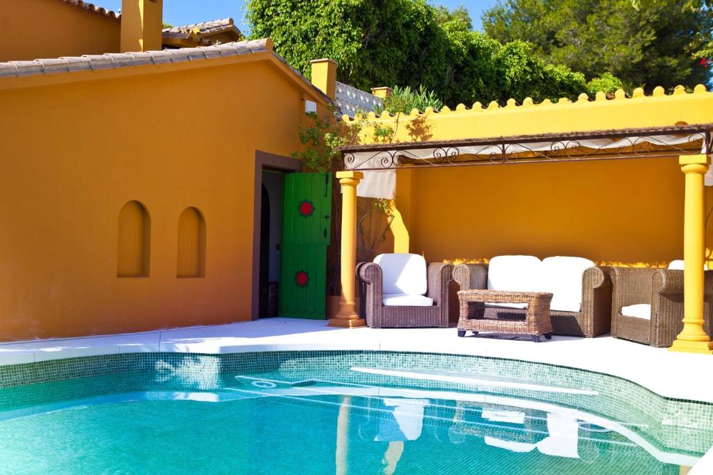 a swimming pool with chairs and a house at Family hotel Al- Ana Marbella in Estepona