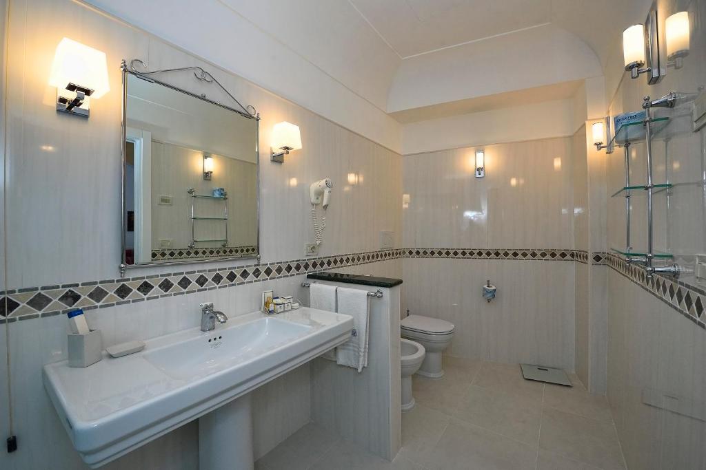 a bathroom with a sink and a toilet and a mirror at Hotel Belvedere in Conca dei Marini