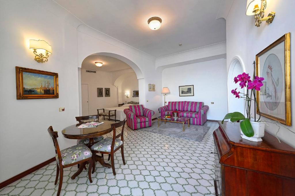 a living room with a table and pink chairs at Hotel Belvedere in Conca dei Marini