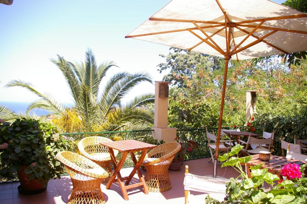 un patio con mesa, sillas y sombrilla en Hotel Bel Tramonto en Marciana