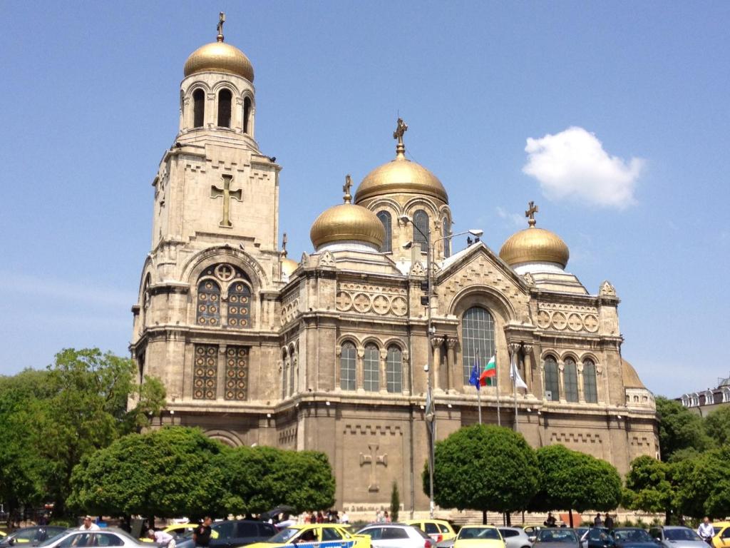 Cathedral Guesthouse في مدينة فارنا: كاتدرائية بها قباب ذهبية وسيارات متوقفة في الأمام