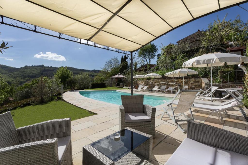 un patio con piscina, sillas y sombrilla en Casale Le Masse, en Greve in Chianti