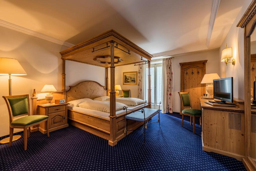 a bedroom with a canopy bed and two chairs at Furggerhof in Tirolo