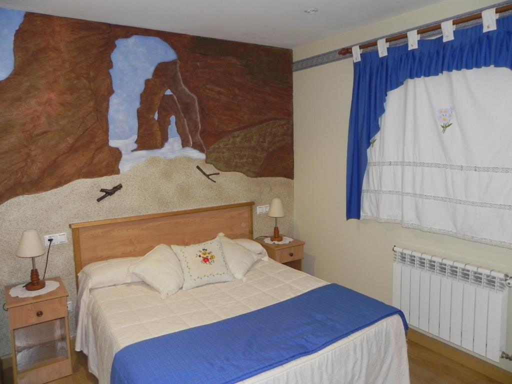 a bedroom with a bed with a painting on the wall at O Lar de Carmiña in Devesa
