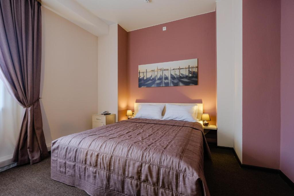トムスクにあるHotel Galereyaの紫の壁のベッドルーム1室(大型ベッド1台付)