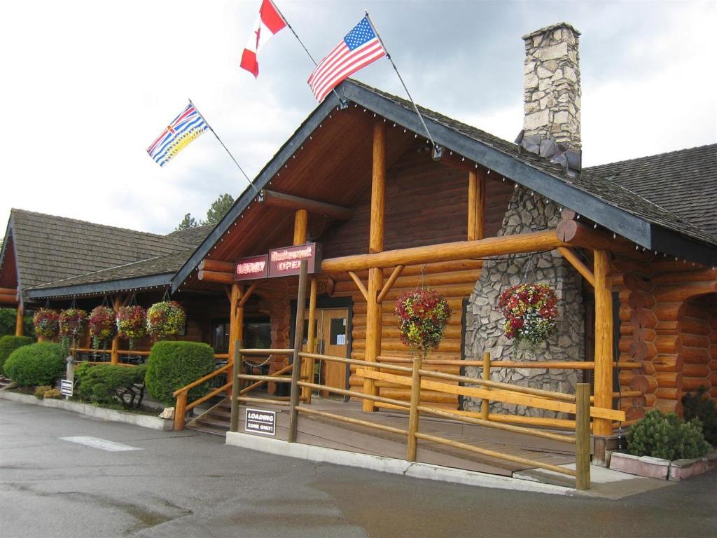 a log cabin with two american flags on it at Cariboo Lodge in Clinton