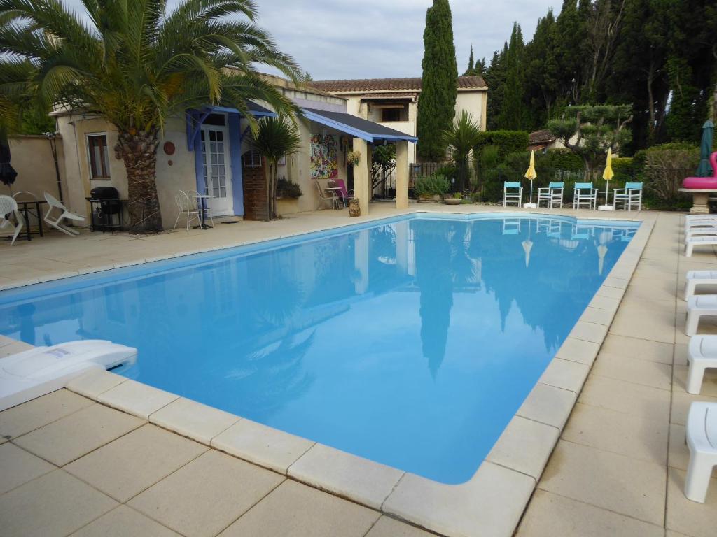 une grande piscine avec des chaises et une maison dans l'établissement Mas Saint Antoine, à Rognonas