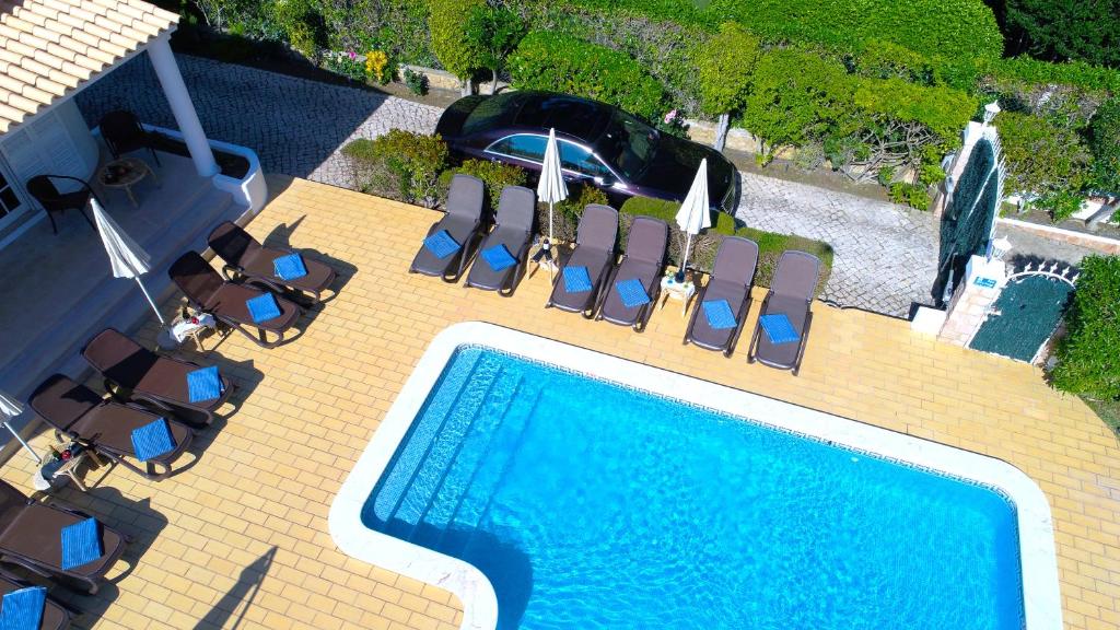 einen Blick über einen Pool mit Stühlen und Sonnenschirmen in der Unterkunft Villa Tenazinha I in Albufeira