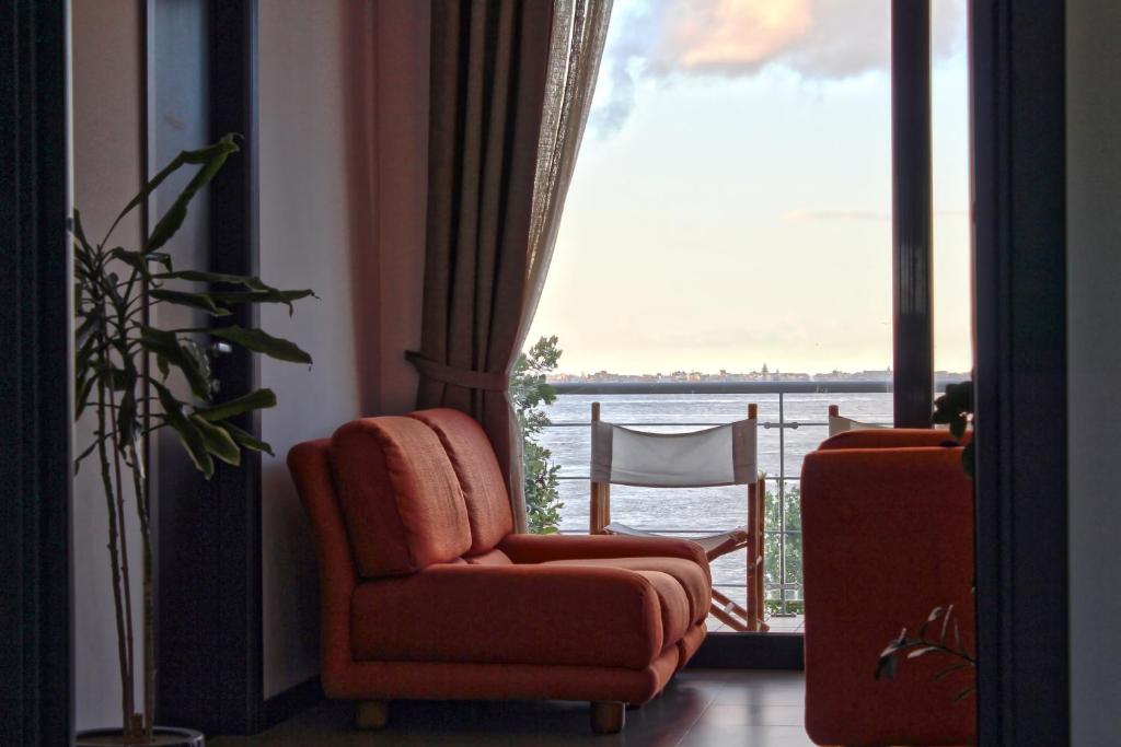 sala de estar con silla y vistas al agua en B&B Sirio, en Villa San Giovanni