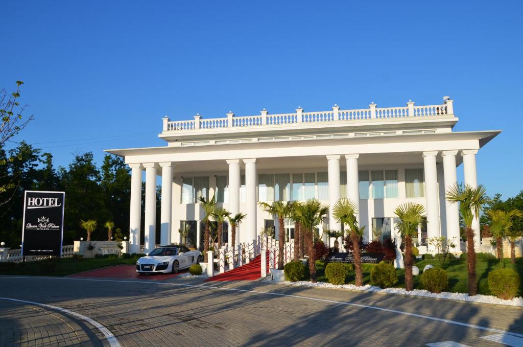 duży biały budynek z samochodem zaparkowanym przed budynkiem w obiekcie Queen Vali Palace w mieście Prilepnica