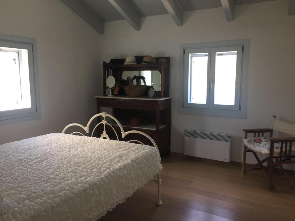 1 dormitorio con 1 cama blanca y 2 ventanas en Seaside Heaven en Otzias