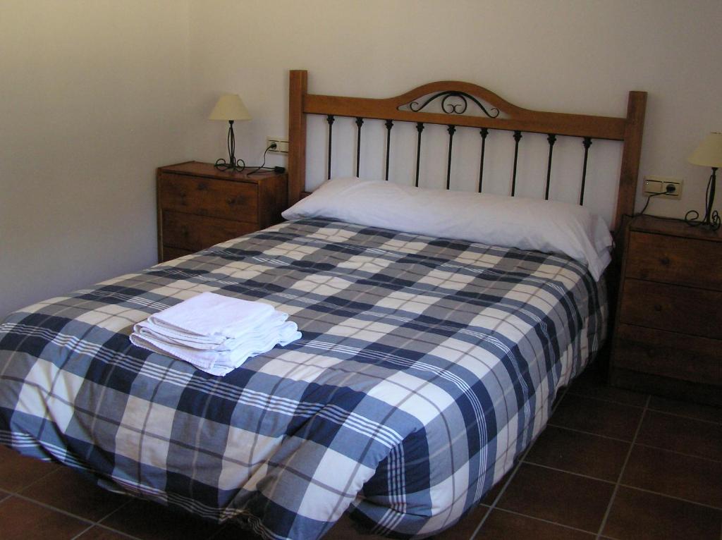 Un dormitorio con una cama con una manta de cuadros azul y blanco en Alojamiento Rural El Chaparral, en Setenil