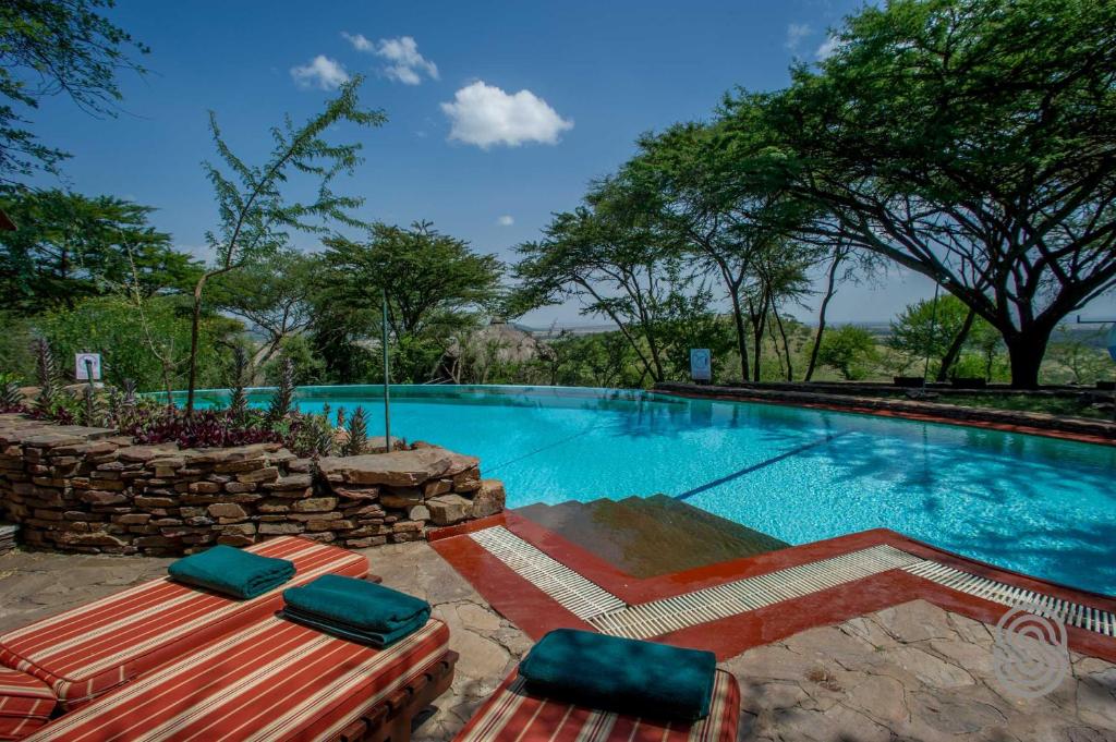 a large swimming pool with two lounge chairs next to it at Serengeti Serena Safari Lodge in Serengeti National Park