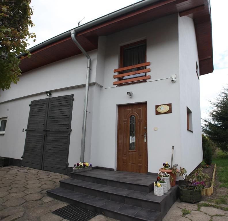 ein weißes Haus mit einer Holztür und einer Treppe in der Unterkunft Mieszkanie Pod Dobrym Aniołem in Czempiń