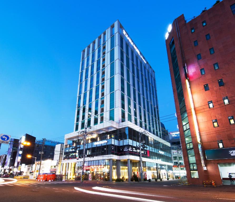 a tall glass building on a city street at night at Solaria Nishitetsu Hotel Busan in Busan