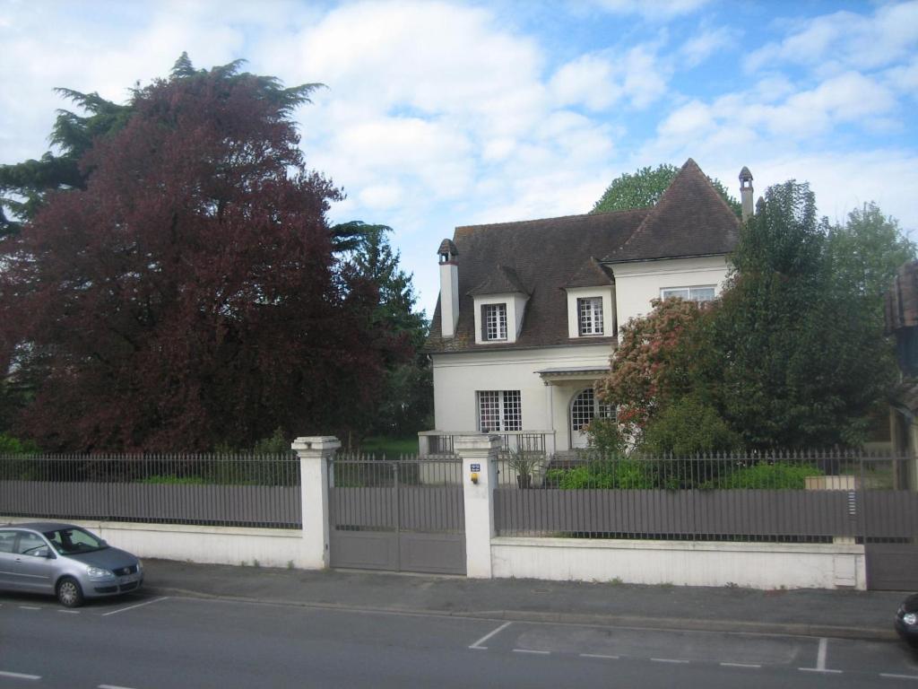 ein weißes Haus mit einem Zaun und einem Auto in der Unterkunft Villa PHILIS in Bergerac