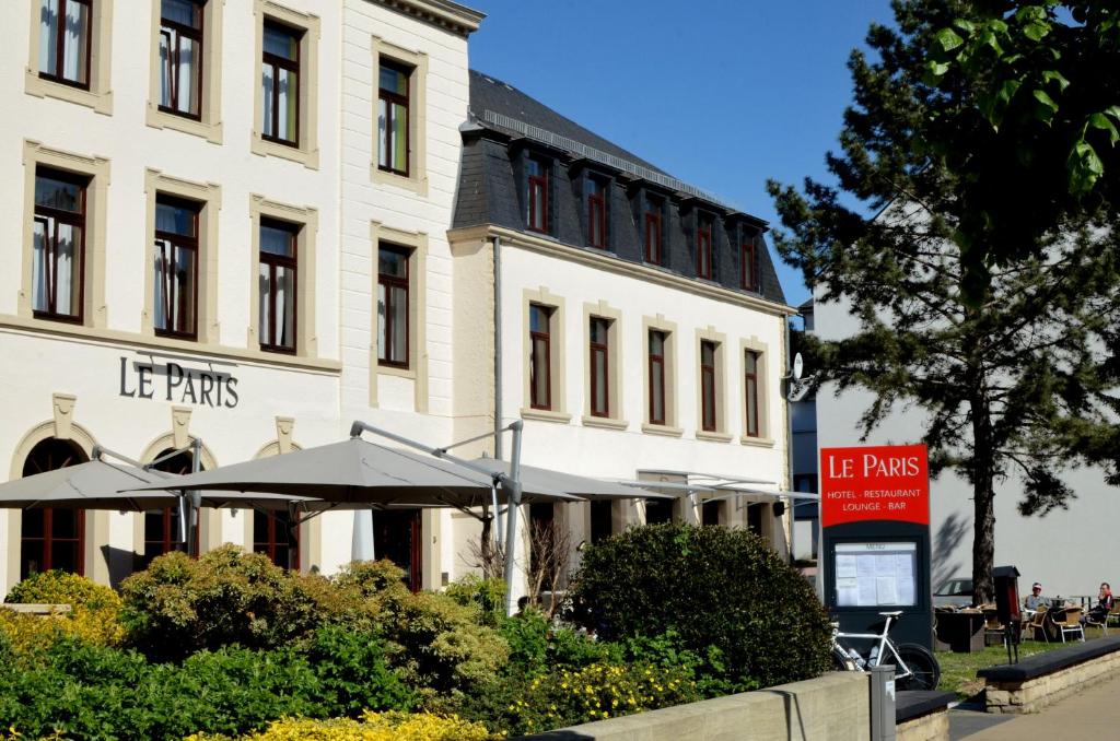 a large white building with an umbrella in front of it at Hotel Restaurant Le Paris in Mondorf-les-Bains
