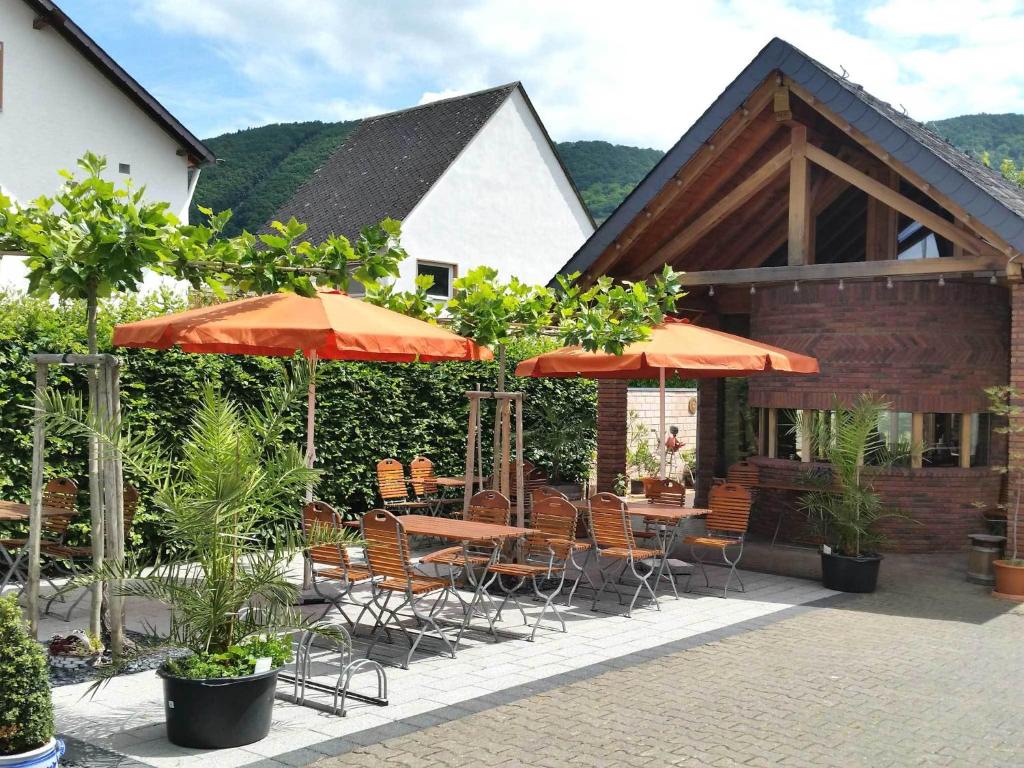 un patio con mesas, sillas y sombrillas en Gästehaus Bollig, en Trittenheim