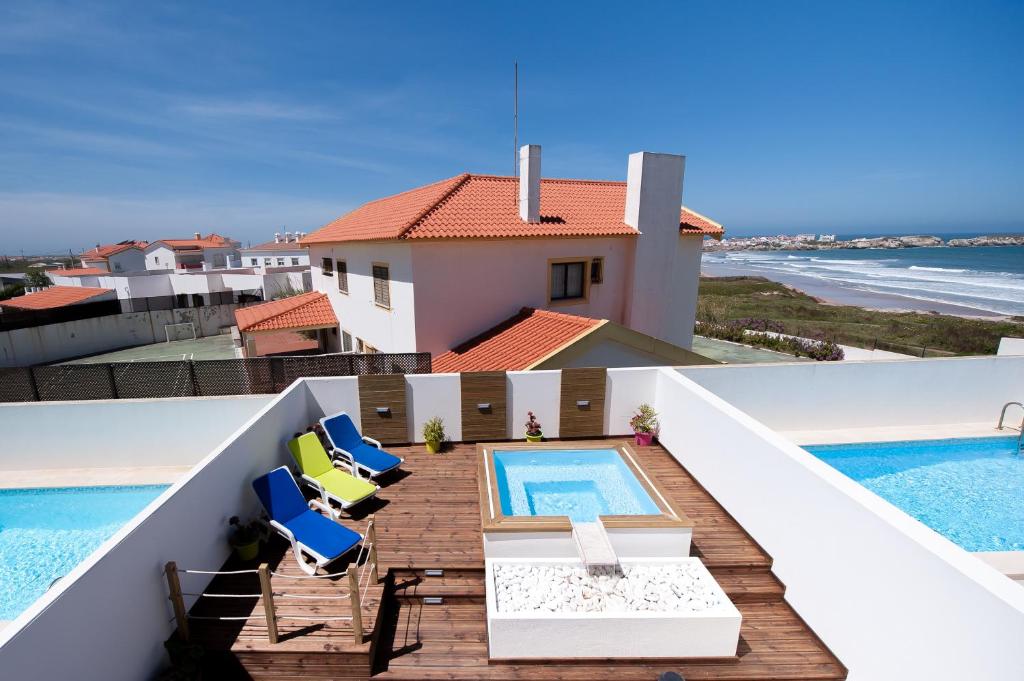 una casa y un balcón con piscina y sillas. en Baleal Beach Holiday Villa, en Baleal