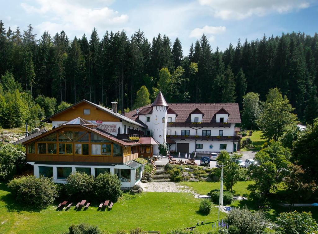ein großes Gebäude auf einem Hügel mit Stühlen im Gras in der Unterkunft Märchenhotel Waldpension Nebelstein in Harbach