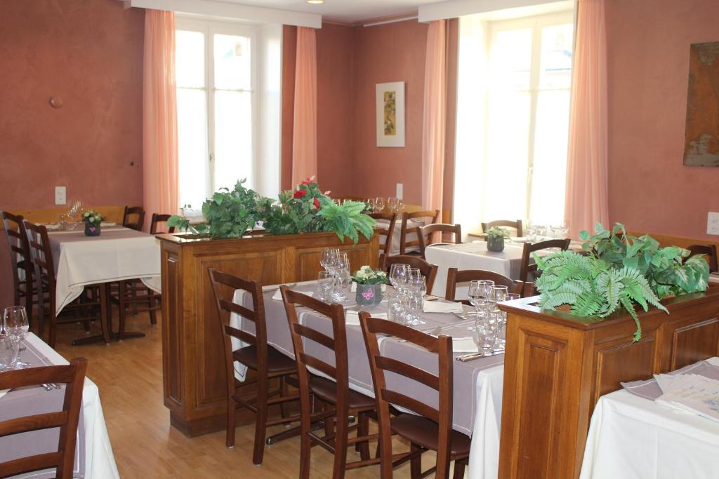 a restaurant with tables and chairs with plants on them at Hôtel de la Gare in Yvonand