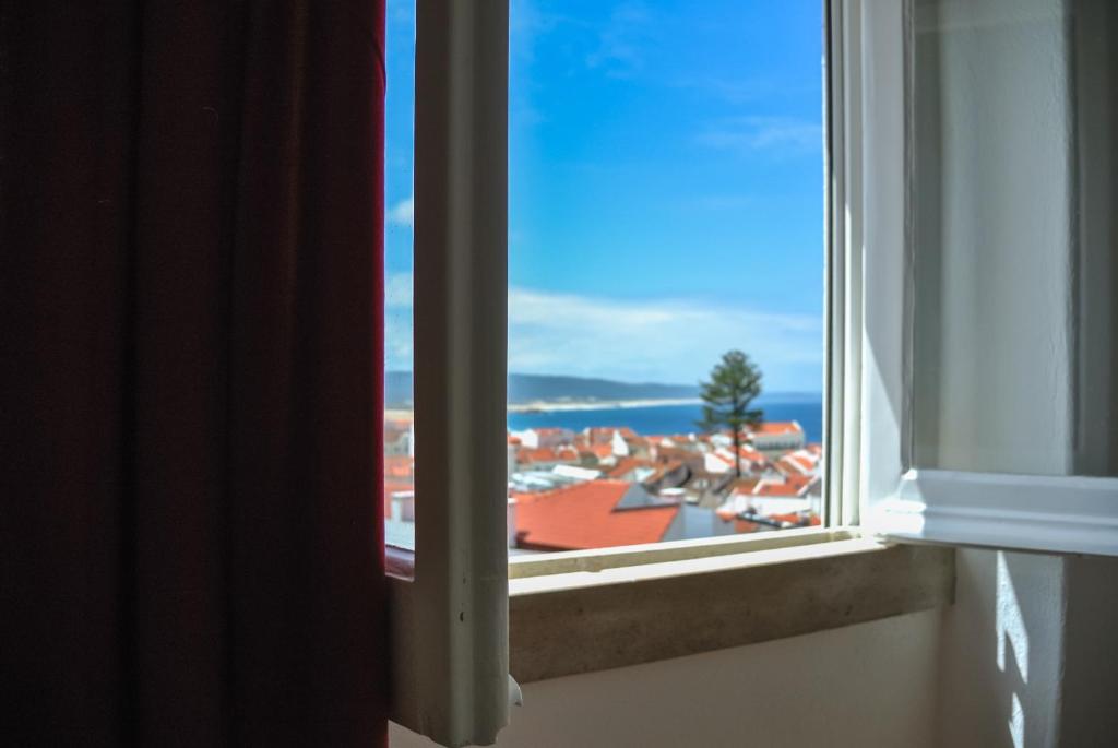 uma janela aberta com vista para uma cidade em Nazaré Hostel - Rooms & Dorms em Nazaré