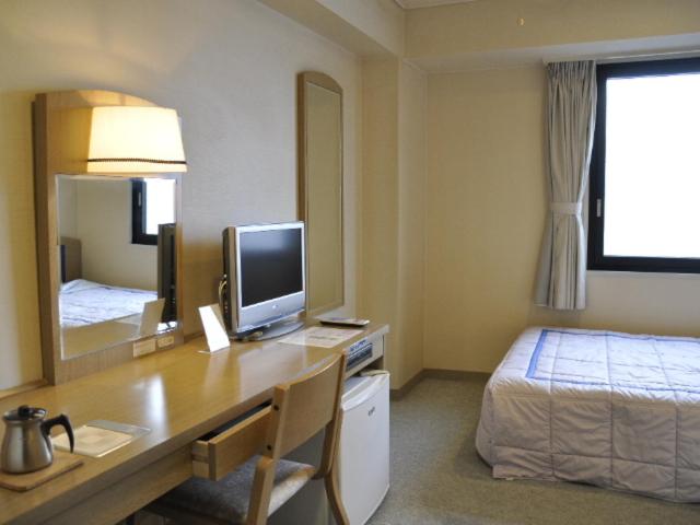 a bedroom with a desk with a computer and a bed at Silk Hotel in Ichinomiya