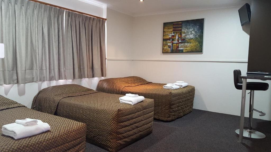 a hotel room with two beds and two ottomans at The Commercial Hotel Motel in Chinchilla