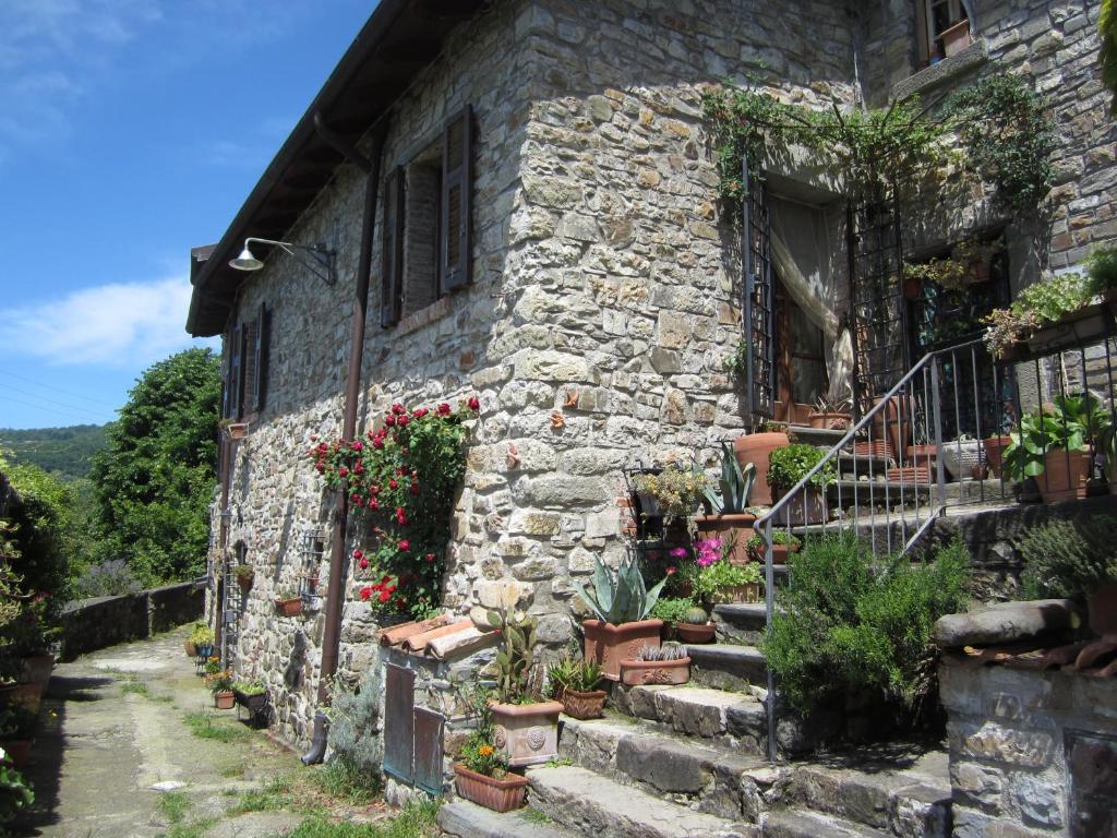 una vieja casa de piedra con plantas a un lado en Poggio delle Rondini, en Bagnone