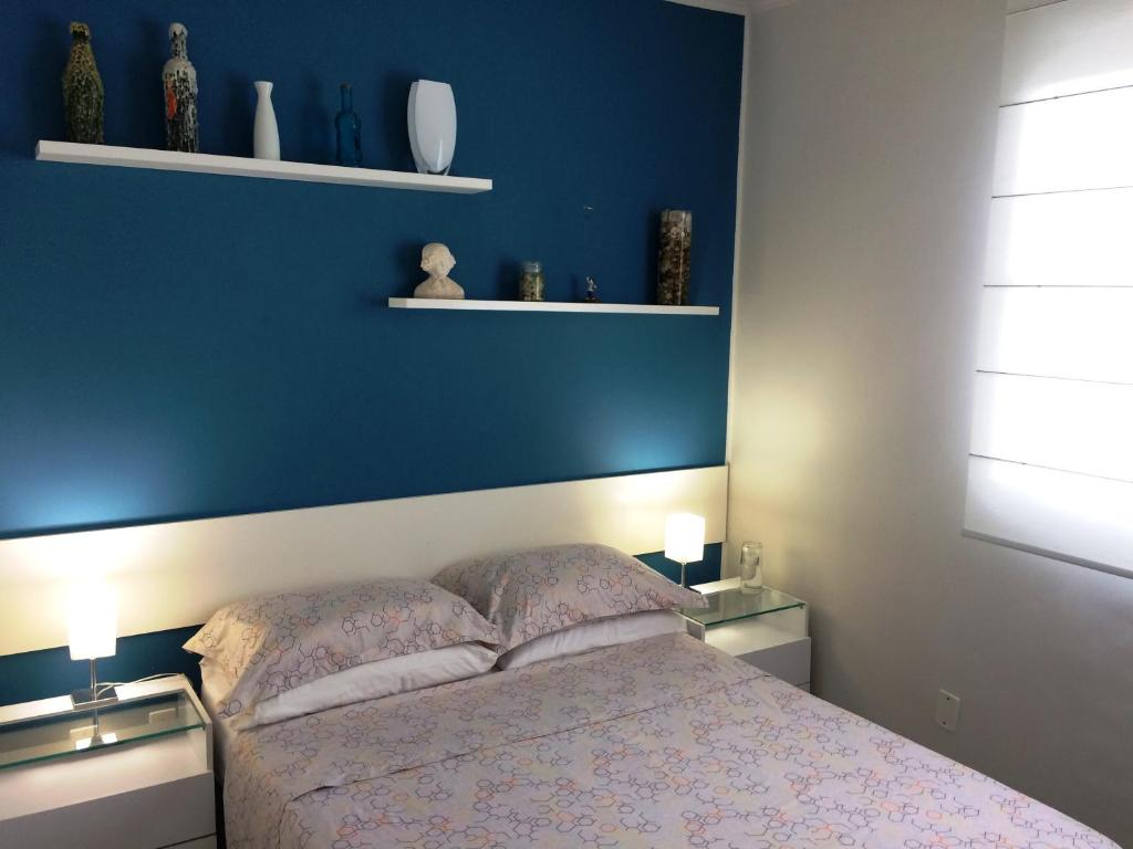 a bedroom with a blue wall and a bed at Apt 1D Aeroporto/Arena in Porto Alegre