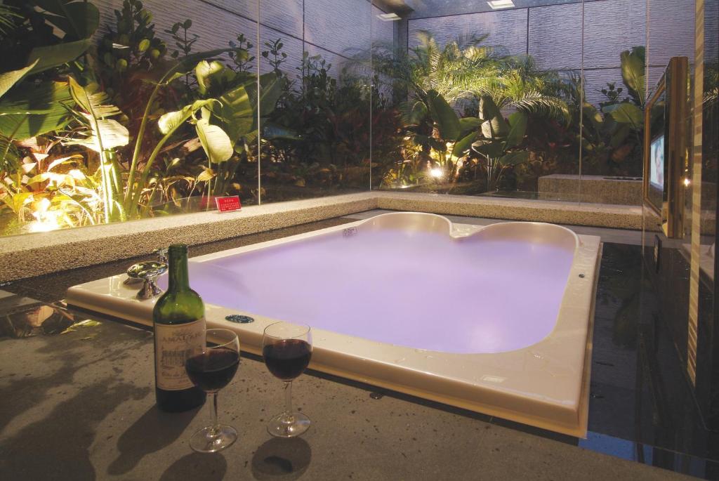 una vasca da bagno con 2 bicchieri di vino e una bottiglia di vino di Q Motel精品旅館 a Tucheng