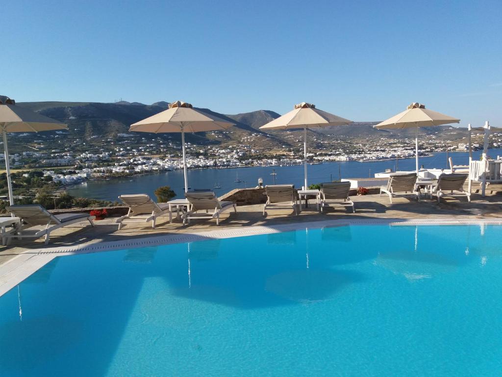 una gran piscina con sillas y sombrillas en Krotiri Bay -adults only, en Parikia