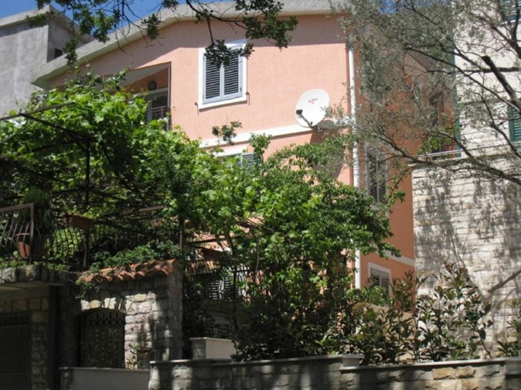 a pink house with a window and trees in front of it at Apartment Stana in Petrovac na Moru