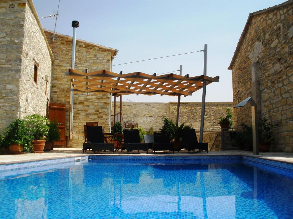 a swimming pool with chairs and a wooden pergola at Anesi House in Skarinou