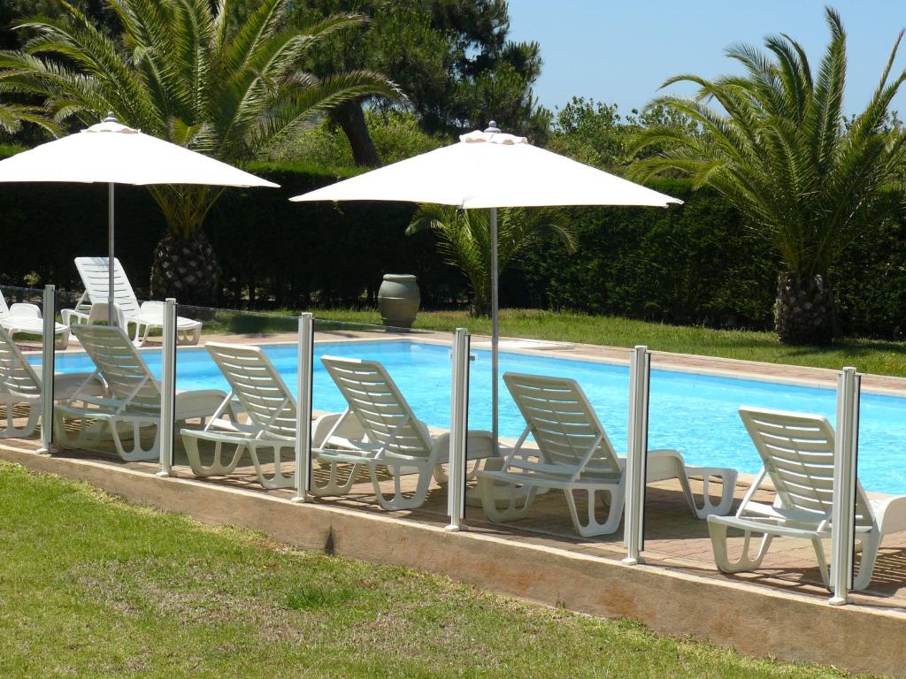 een rij stoelen en parasols naast een zwembad bij Residence les Bell'ombres in Cargèse