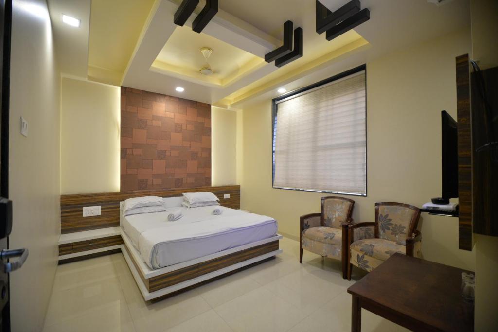 a bedroom with a bed and two chairs and a window at Hotel Radhe Krishna in Solapur