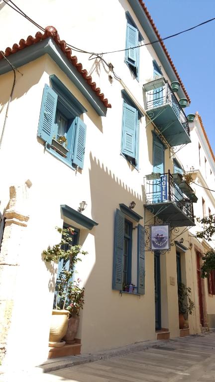 un edificio bianco con finestre blu e balconi di Polyxenia Hotel a Nauplia