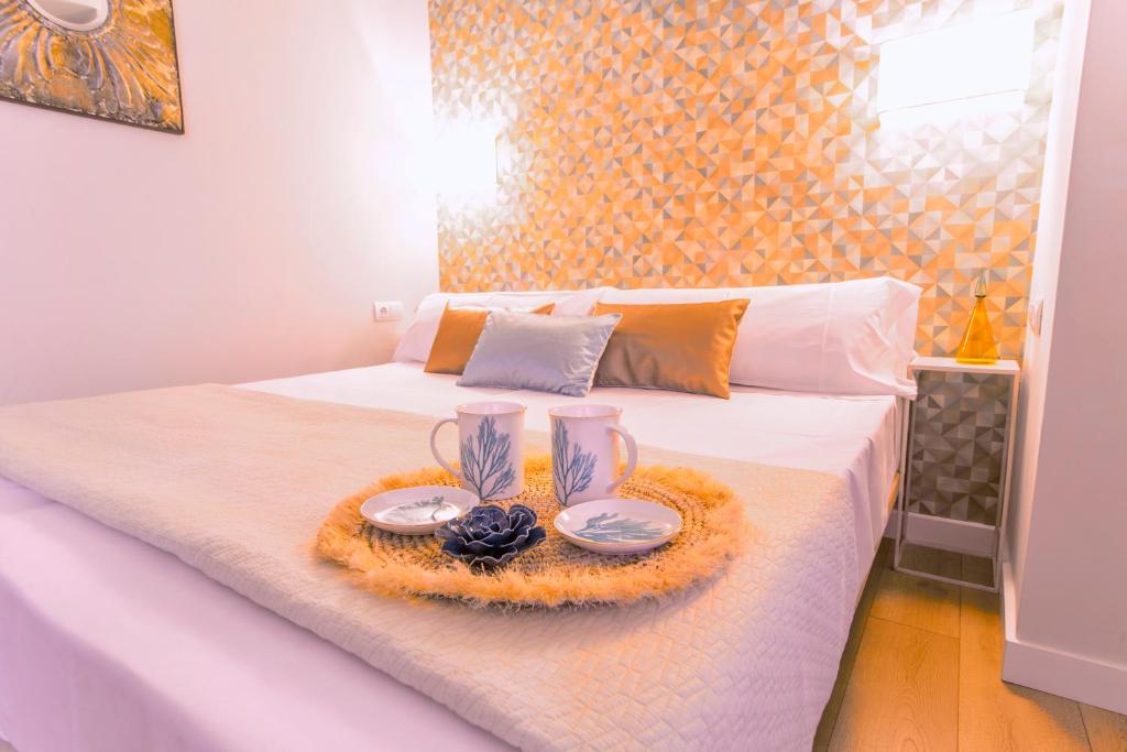 Una cama con una bandeja con dos platos. en Apartamento Malaga Beach, en Málaga