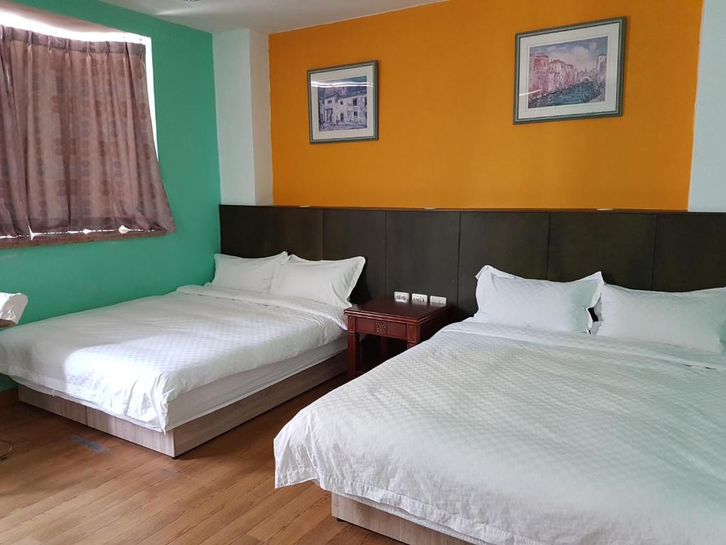 花蓮市的住宿－微風民宿，绿橙色墙壁的客房内的两张床