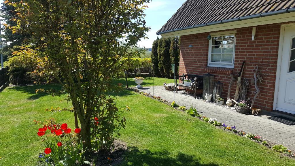 uma casa com um quintal com uma árvore e flores em Ferienwohnungen An der Ostsee em Wittenbeck
