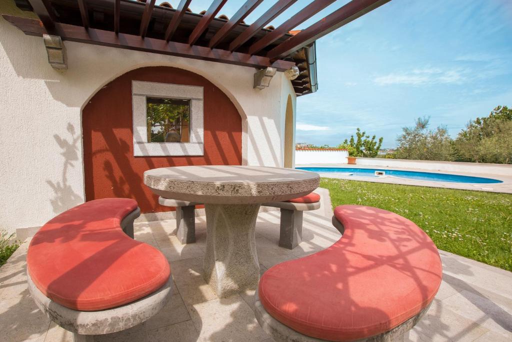 un patio con mesa y 2 sillas rojas en Apartment Kampel, en Koper