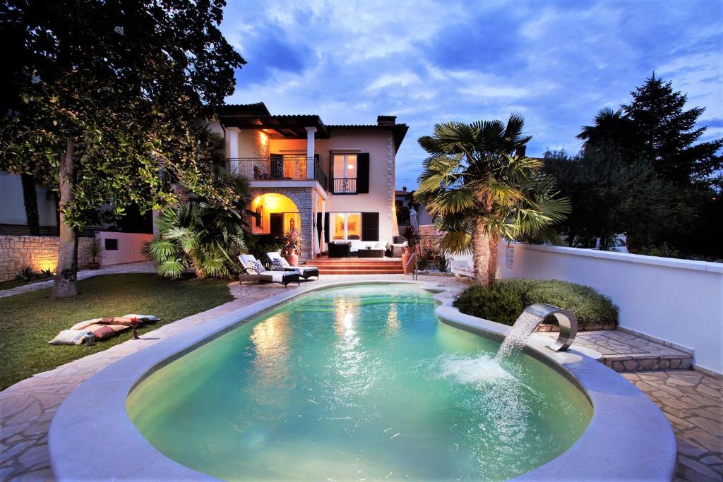 a swimming pool with a fountain in front of a house at Villa Magnolia Umag in Umag