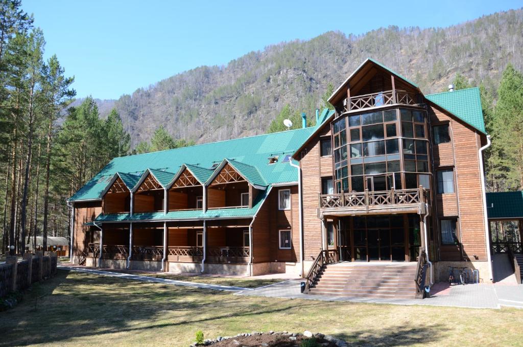 a large wooden building with a green roof at Hotel Zolotye Peski in Ust'-Muny