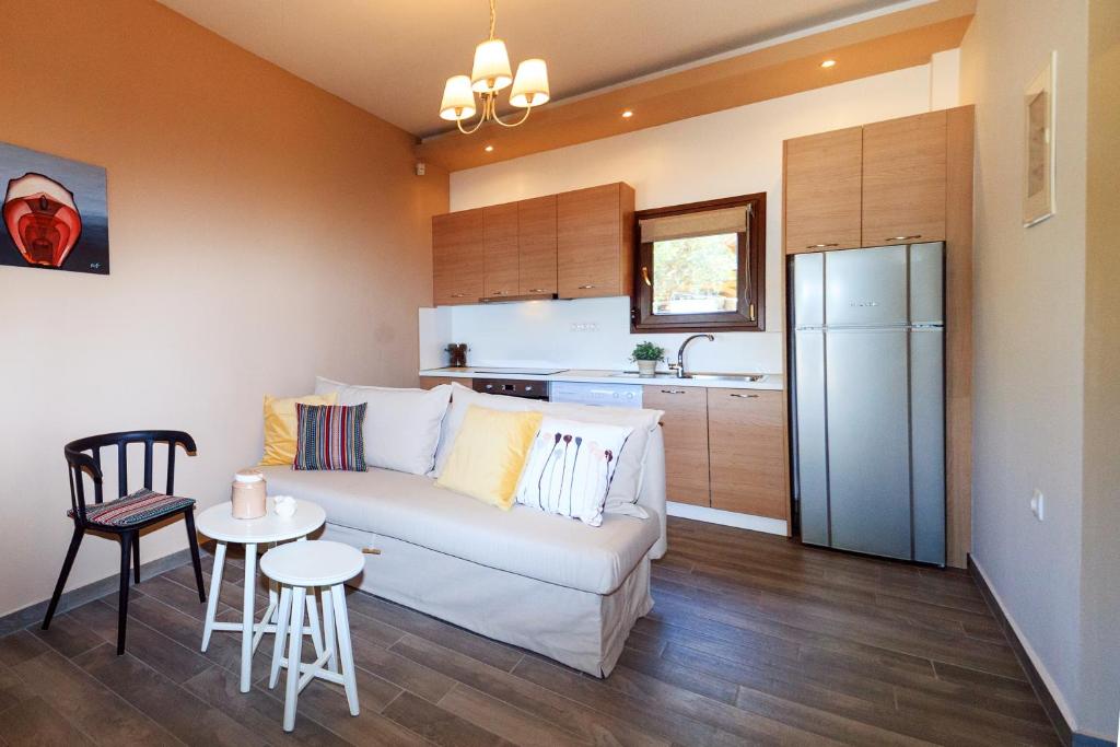a living room with a white couch and a kitchen at Kissos Apartments in Vourvourou