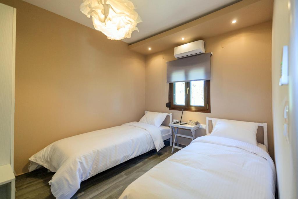 two beds in a small room with a window at Kissos Apartments in Vourvourou