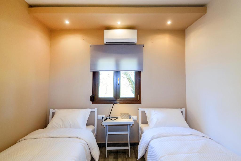 two beds in a room with a table and a window at Kissos Apartments in Vourvourou
